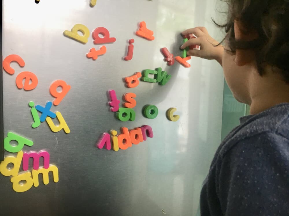 Niño jugando con imanes del alfabeto en el refrigerador