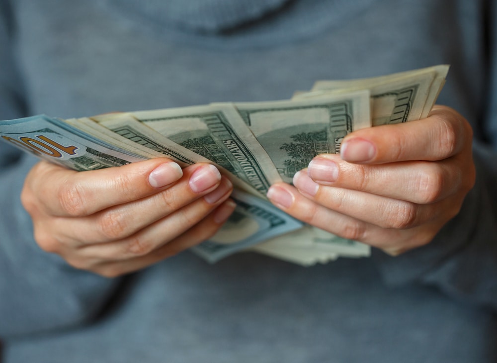 Primer plano de manos de mujer sosteniendo dinero después de cobrar un cheque