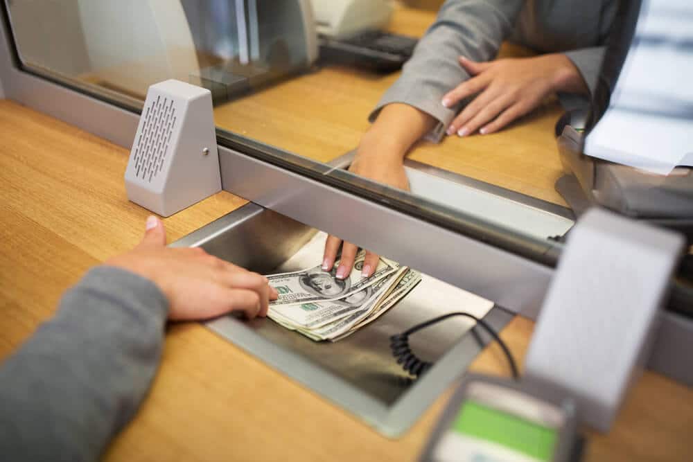 Cajero de banco dando efectivo a un cliente en un banco abierto hasta tarde