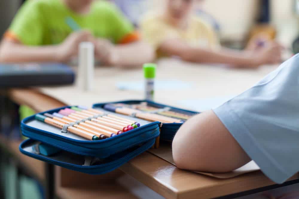 Niños en la escuela usando útiles escolares en su escritorio