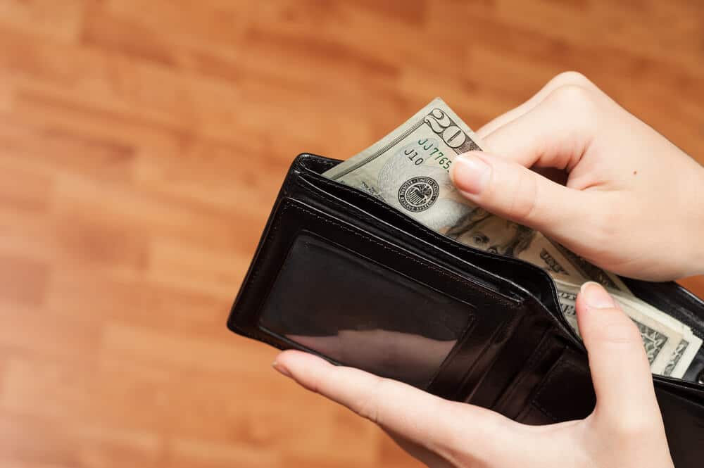 Manos de mujer sacando efectivo de la billetera para pagar un giro postal