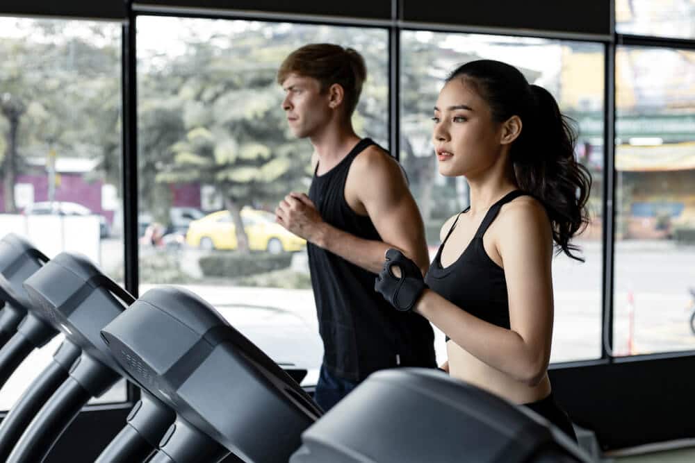 Hombre y mujer haciendo ejercicio en cintas de correr en un gimnasio