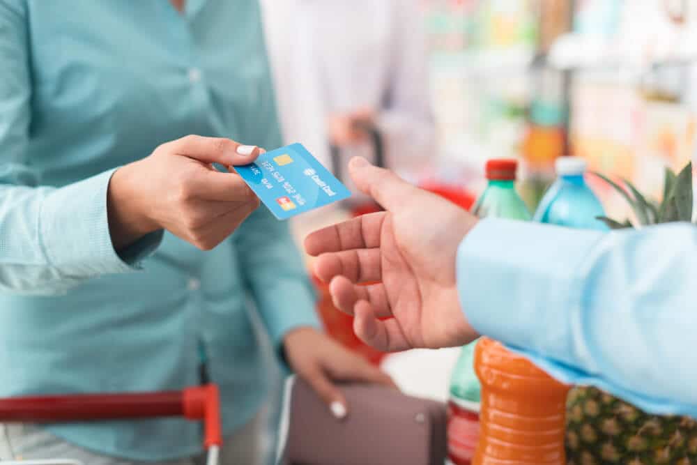 Mujer pagando comestibles con tarjeta de crédito