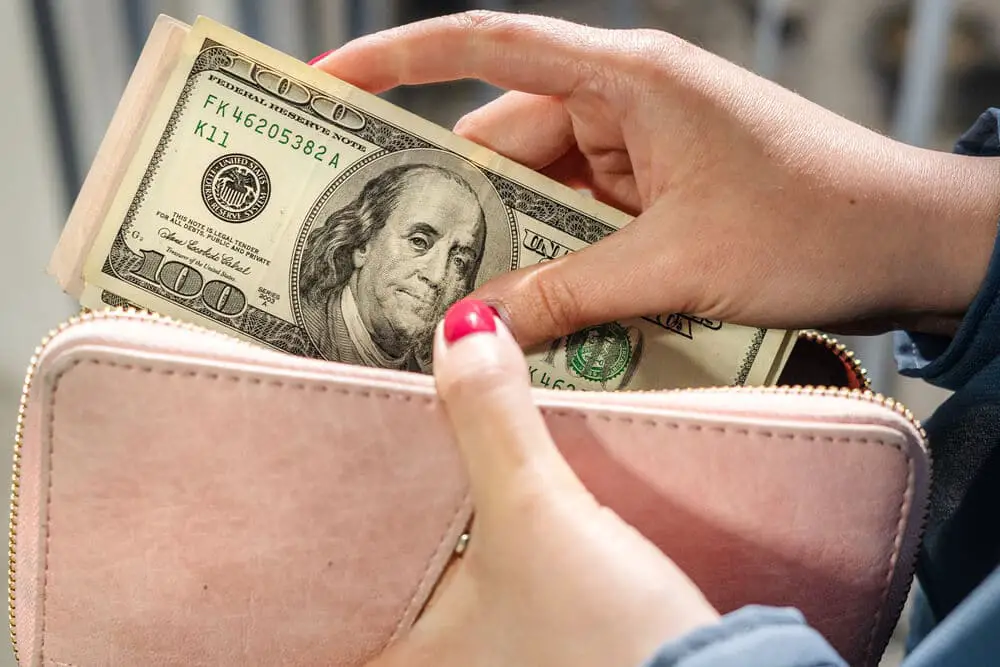 Mujer poniendo dinero en efectivo en la billetera después de cobrar el cheque