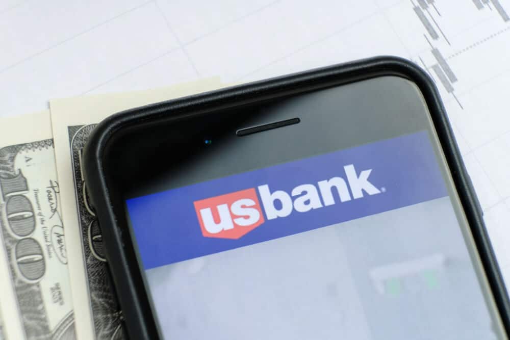 Logotipo de US Bank en un teléfono con papeles y dinero