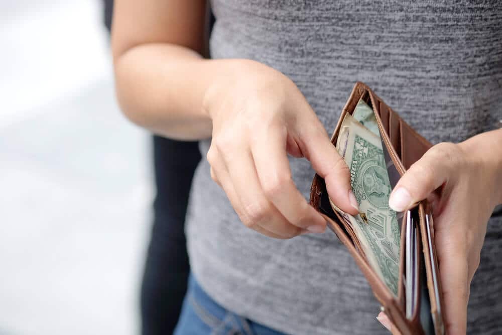 Mujer sosteniendo billetera con dinero dentro
