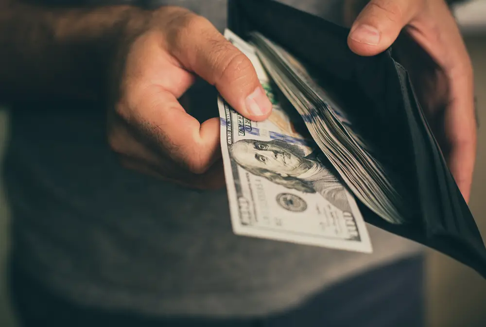 Hombre poniendo dinero en efectivo en la billetera después de cobrar un cheque