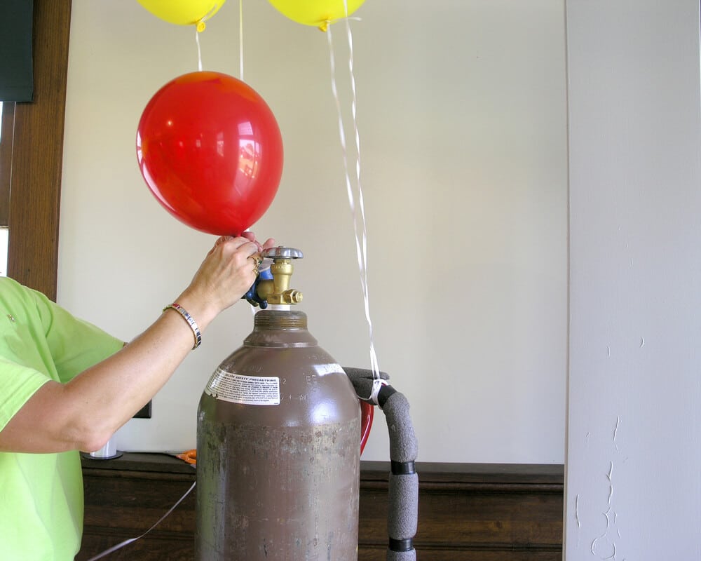 Hombre llenando un globo con helio de un tanque