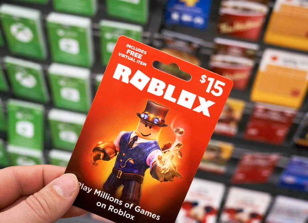 Mano de una persona que sostiene una tarjeta de regalo de Roblox en una tienda que vende tarjetas de regalo de Roblox