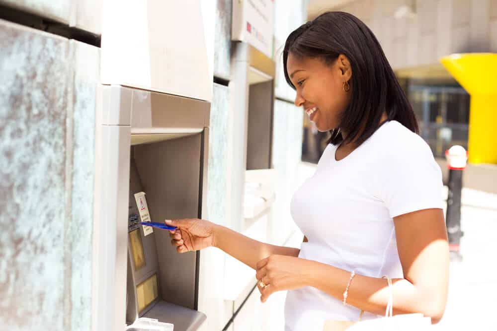 mujer joven retirando efectivo de un cajero automático