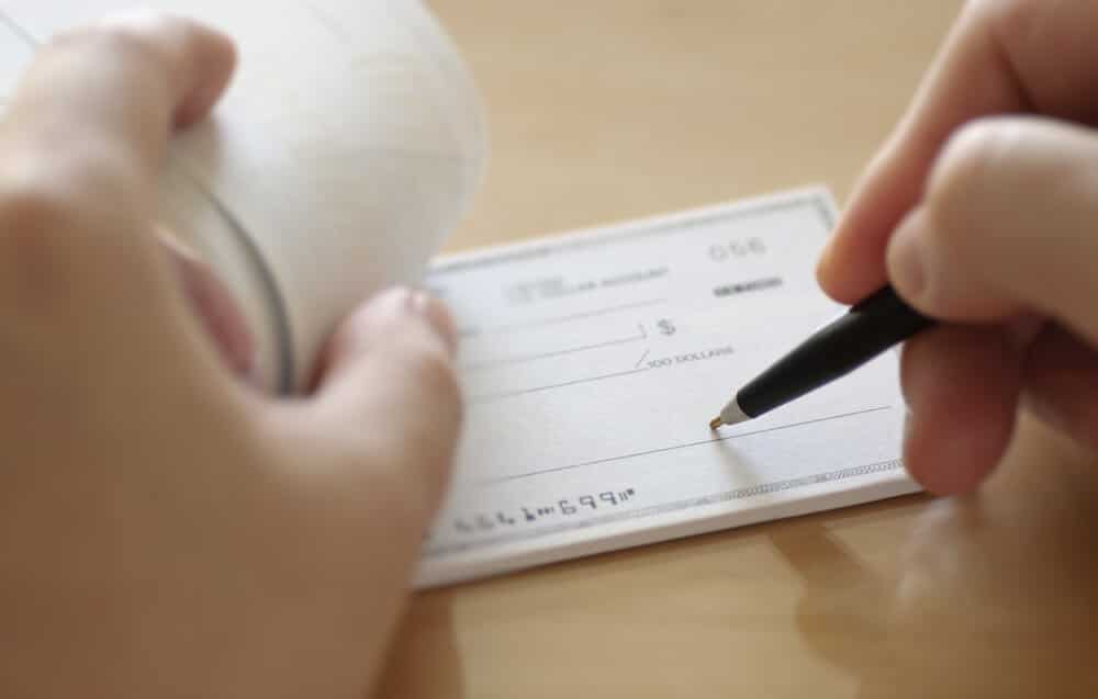 Manos de la persona escribiendo un cheque